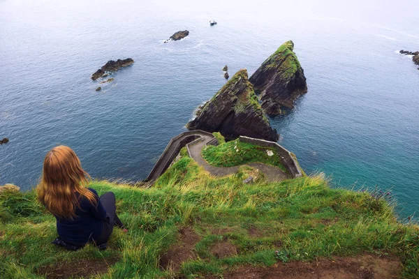 女孩坐在爱尔兰海洋的悬崖上 — 图库照片