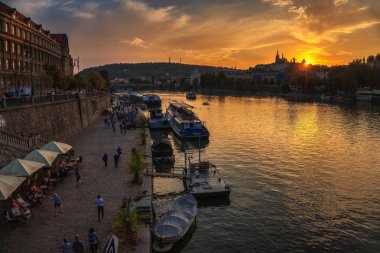 Gün batımında Prag'da Vltava Nehri boyunca insanlar yürümek