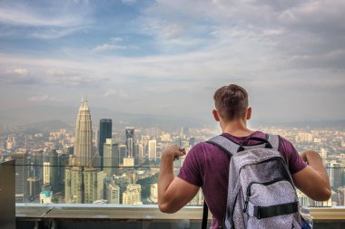Bir sırt çantası ile turist Kuala Lumpur silüetinin panoramik manzarasına sahiptir