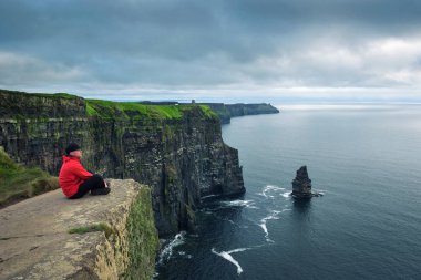 Moher kayalığında oturan Hiker