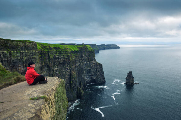 Hiker sitting at the cliffs of Moher