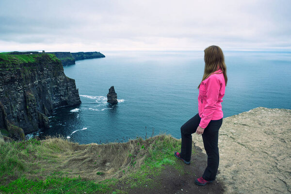 Young girl standing at the cliffs of Moher