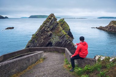 Dunquin İskelesi'nde dev kayalıkları ve İrlanda adalarını izleyen turist, Dingle Yarımadası, İrlanda