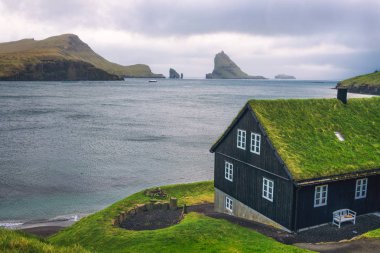 Arka planda Drangarnir deniz yığını ile Faroe Adaları sahilinde ev