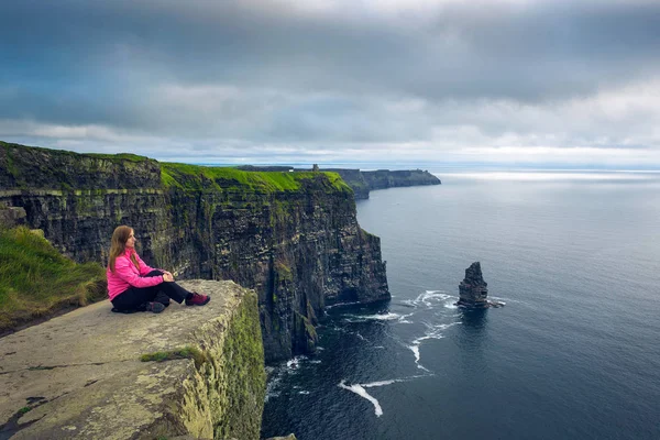 Moher Kayalıkları oturan genç kadın — Stok fotoğraf