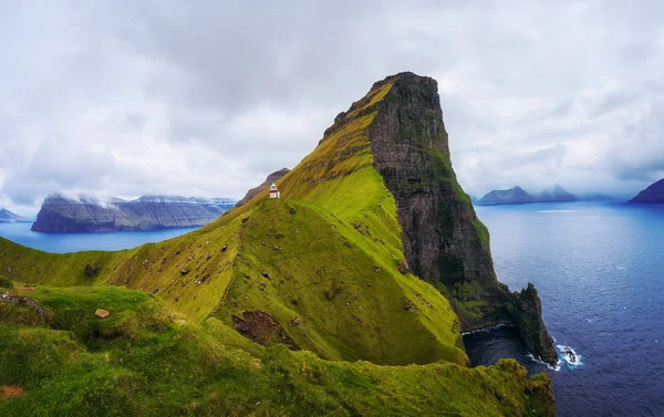 Pequeno farol localizado perto de enormes falésias na ilha de Kalsoy, Ilhas Faroé — Fotografia de Stock