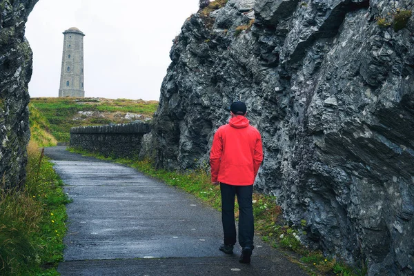Joven caminando hacia el faro de Wicklow Head en Irlanda — Foto de Stock