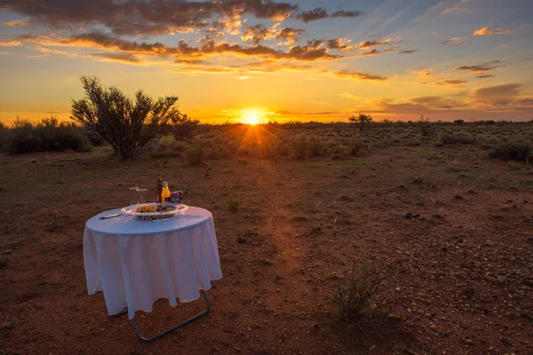Mesa de picnic con aperitivos y bebidas en el desierto de Kalahari al atardecer — Foto de Stock