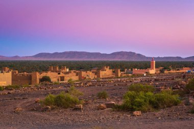 Arka planda Atlas dağları ile faslı bir köyün üzerinde gün batımı