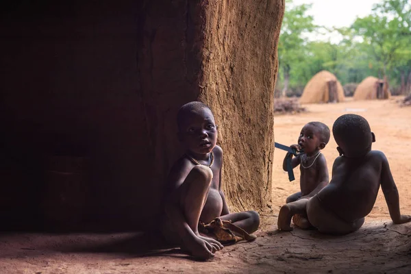 Tři děti kmene Himba v Namibii hrají v jejich chatě — Stock fotografie