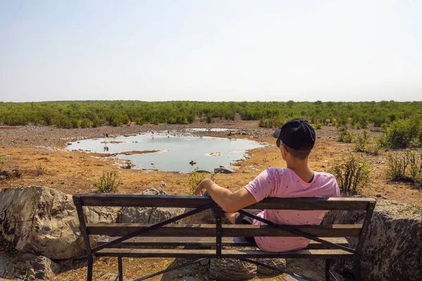 Turista espera vida silvestre en el pozo de agua de Moringa cerca de Halali, Etosha, Namibia — Foto de Stock