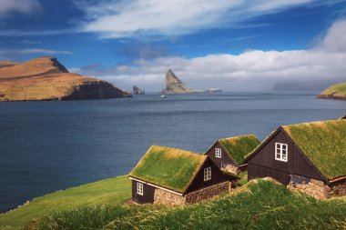 Faroe Adaları 'ndaki Bour Köyü' nün arka planında Drangarnir deniz yığınları var.