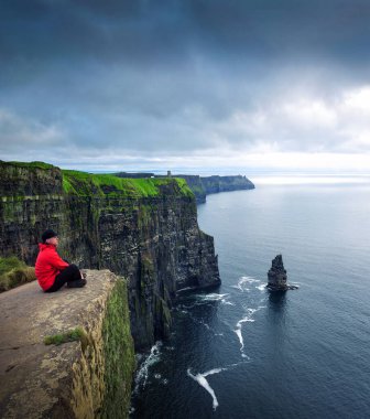 Moher kayalığında oturan Hiker
