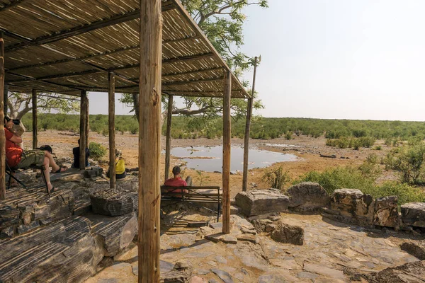 Los turistas esperan la vida silvestre en el pozo de agua de Moringa cerca de Halali, Etosha, Namibia — Foto de Stock