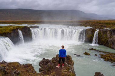 İzlanda 'daki Godafoss şelalesinde duran yürüyüşçü.