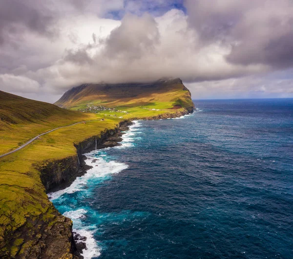 Veduta aerea di una strada che costeggia la costa fino ad un villaggio sulle Isole Faroe — Foto Stock