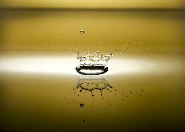 Een Plons Water Met Een Reflectie Een Gele Achtergrond — Stockfoto