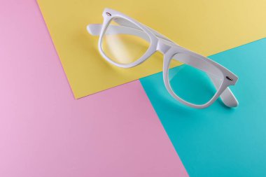 Arka planda beyaz gözlük, üst manzara. Renkli kağıt arkaplan düzlüğü olan modaya uygun minimal biçim.