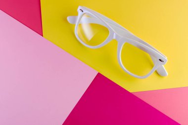 Arka planda beyaz gözlük, üst manzara. Renkli kağıt arkaplan düzlüğü olan modaya uygun minimal biçim.