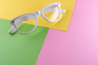 Arka planda beyaz gözlük, üst manzara. Renkli kağıt arkaplanlı modaya uygun minimal biçim