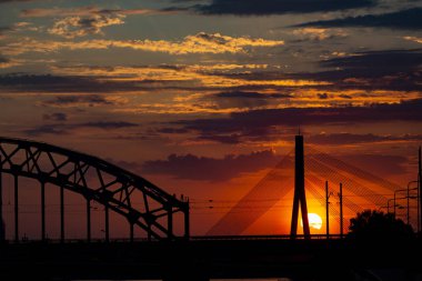 Asma köprü ve gün batımında demiryolu köprüsü. Riga, Letonya