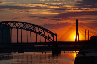 Asma köprü ve gün batımında demiryolu köprüsü. Riga, Letonya