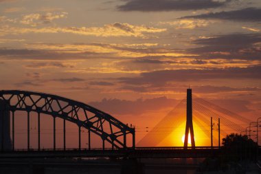 Asma köprü ve gün batımında demiryolu köprüsü. Riga, Letonya