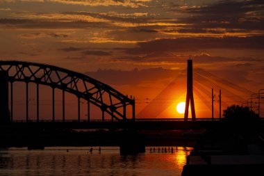 Asma köprü ve gün batımında demiryolu köprüsü. Riga, Letonya