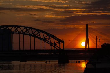 Asma köprü ve gün batımında demiryolu köprüsü. Riga, Letonya