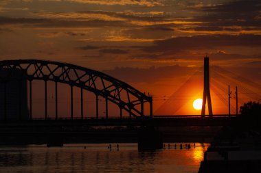 Asma köprü ve gün batımında demiryolu köprüsü. Riga, Letonya