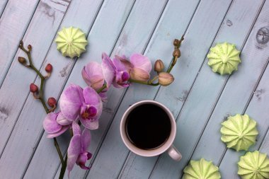 Bir fincan kahve, marşmelov ve açık ahşap bir masada bir orkide. en üstteki görünüm.