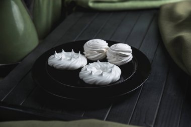 Hayat, marşmelov ve krema siyah bir tabakta, siyah bir tahta masada.