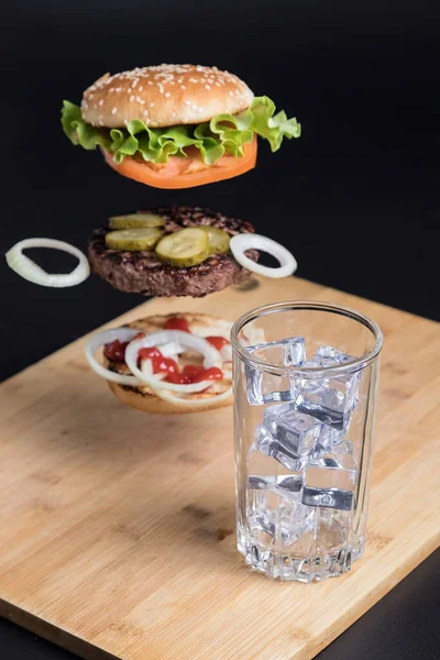 Köstlicher Burger Mit Schwebenden Zutaten Auf Dem Hintergrund Eines Holztisches — Stockfoto