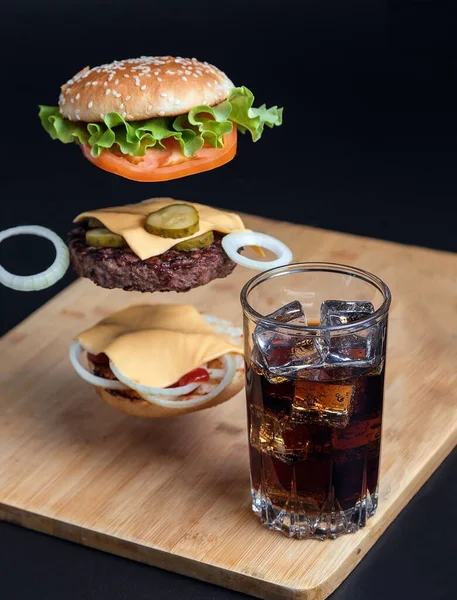 Köstlicher Burger Mit Schwebenden Zutaten Auf Dem Hintergrund Eines Holztisches — Stockfoto