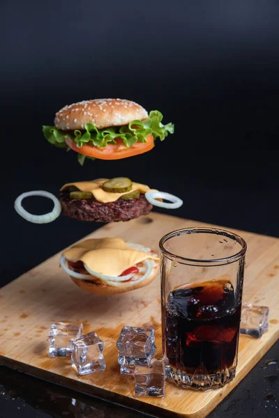 Ahşap Bir Masanın Arka Planında Yüzen Malzemelerle Lezzetli Bir Hamburger — Stok fotoğraf
