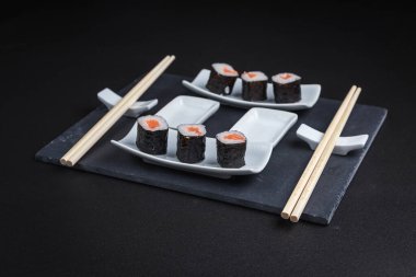 Karanlık bir arka planda geleneksel Japon yemekleri. Suşi ruloları. Asya yemekleri. Akşam yemeği partisi. 