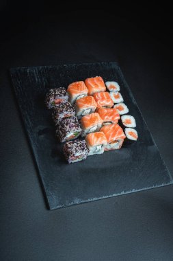 Karanlık bir arka planda geleneksel Japon yemekleri. Suşi ruloları. Asya yemekleri. Akşam yemeği partisi. 