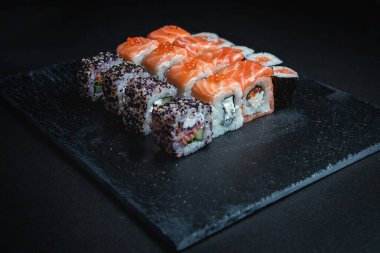 Karanlık bir arka planda geleneksel Japon yemekleri. Suşi ruloları. Asya yemekleri. Akşam yemeği partisi. 