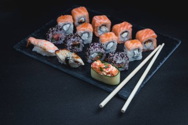 Karanlık bir arka planda geleneksel Japon yemekleri. Suşi ruloları. Asya yemekleri. Akşam yemeği partisi. 