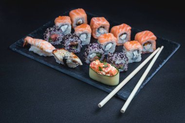 Karanlık bir arka planda geleneksel Japon yemekleri. Suşi ruloları. Asya yemekleri. Akşam yemeği partisi. 