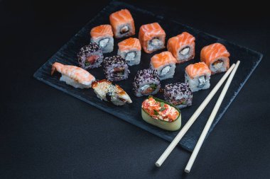 Siyah arka planda suşi. Suşi restoranı menüsü yapmak için mükemmel. Japon mutfağı, Doğu kültürü.