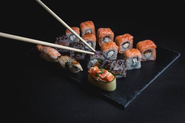 Siyah arka planda suşi. Suşi restoranı menüsü yapmak için mükemmel. Japon mutfağı, Doğu kültürü.