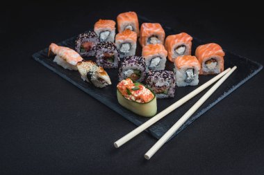 Siyah arka planda suşi. Suşi restoranı menüsü yapmak için mükemmel. Japon mutfağı, Doğu kültürü.