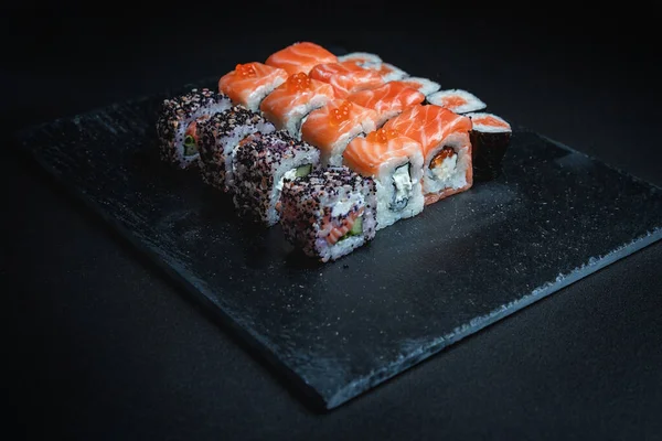 Karanlık bir arka planda geleneksel Japon yemekleri. Suşi ruloları. Asya yemekleri. Akşam yemeği partisi. 