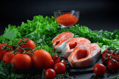 Yakından bir parça kırmızı balık. Bölgesel somon. Sebzeli ve otlu taze balık. Domates ve salata..