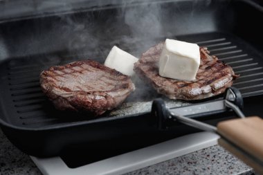 Izgara tavasında pişmiş büyük bir parça taze et. Et tereyağında kızarır. Etteki şeritler. Kızartma tavası..