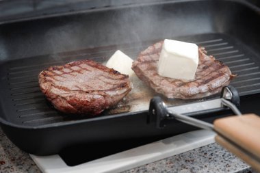 Izgara tavasında pişmiş büyük bir parça taze et. Et tereyağında kızarır. Etteki şeritler. Kızartma tavası..