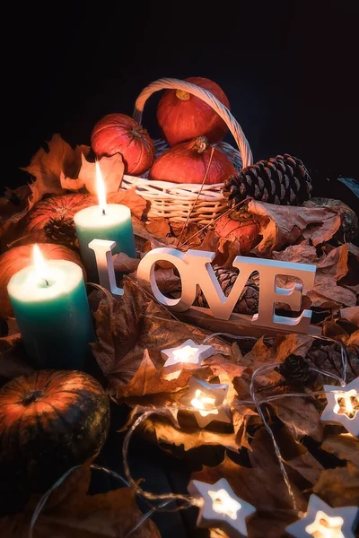 Autumn harvest of pumpkins. Pumpkin in a white basket. Yellow leaves. The inscription love.