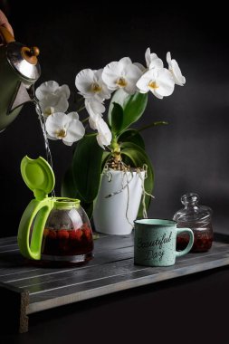 Koyu ahşap bir masada çay seti. Beyaz orkide.