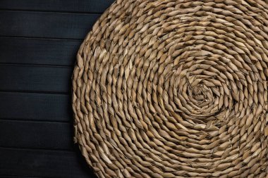 Doğal hasır masa. Mat yuvarlak hasır, merkez spiral, karanlık tahtalardan yapılmış bir masanın üzerinde.
